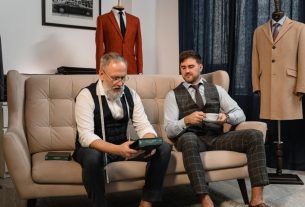 Two well-dressed men enjoying tea in an elegant tailoring workshop.